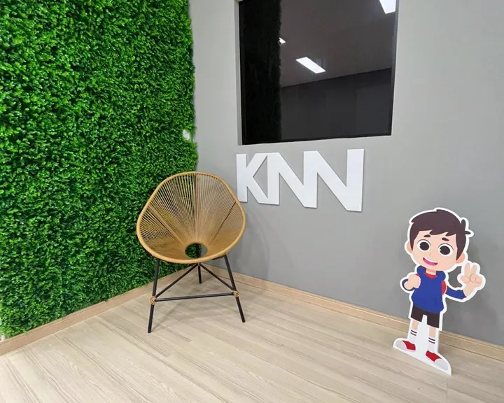 Cantinho de espera com parede verde e o logo da KNN