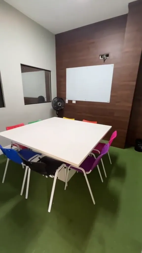 Sala da turma kids em Brás Cubas, com cadeiras coloridas em volta de uma mesa só